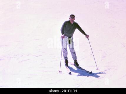 Uomo su coppia di sci sulla pista da sci in posa per foto ca. 1960s Foto Stock