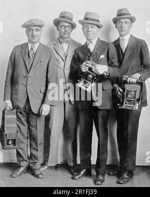 Foto di archivio: Ritratto di gruppo di quattro membri della Casa Bianca News Photographers' Association, in piedi, di fronte, tenendo telecamere ca. 1922-1926 Foto Stock