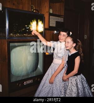 Una giovane ragazza punta ad un pesce in un carro armato sulla parte superiore di un insieme televisivo alla casa della sua nonna in Arkansas ca. 1958 Foto Stock