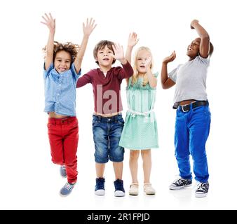 Gioia, salto e ritratto di bambini in studio per la diversità, gli amici e il gioco. Felicità, gioventù e sorriso con gruppo di bambini isolati su bianco Foto Stock