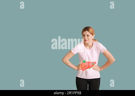 Donna che soffre di dolore al fegato su sfondo colorato. Problema di epatite Foto Stock