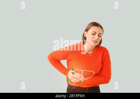 Giovane donna che soffre di dolore al fegato su sfondo chiaro. Problema di epatite Foto Stock