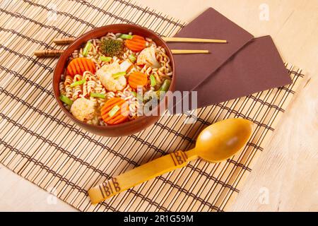 Tradizionale pasto asiatico istantaneo noodles con verdure su sfondo di legno Foto Stock