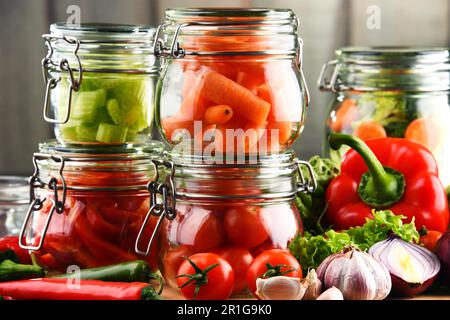 I vasetti con marinata di alimenti e verdure crude sul bordo di taglio Foto Stock