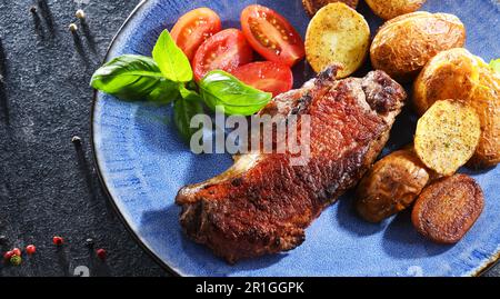 Bistecca di manzo in padella con patate fritte e pomodori ciliegini Foto Stock