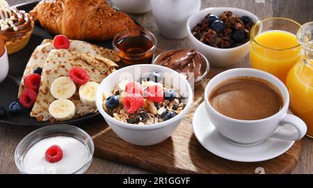 La colazione viene servita con caffè, succo d'arancia, pancake, croissant, cereali e frutta Foto Stock