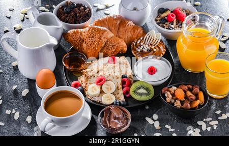 La colazione viene servita con caffè, succo d'arancia, pancake, croissant, cereali e frutta Foto Stock