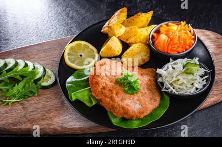 Cotoletta di maiale impanata ricoperta di pangrattato con patate e insalate di verdure Foto Stock