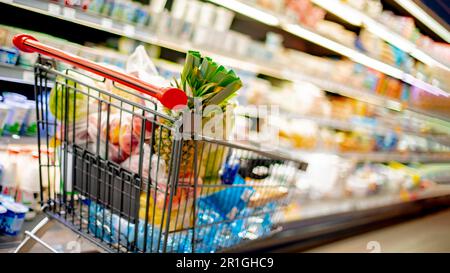 Un carrello con prodotti alimentari in un supermercato Foto Stock
