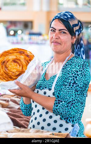 Samarcanda, Uzbekistan - 10 Maggio 2019: Donna vendita di pane a Siab bazaar nel centro di Samarcanda, Uzbekistan Foto Stock