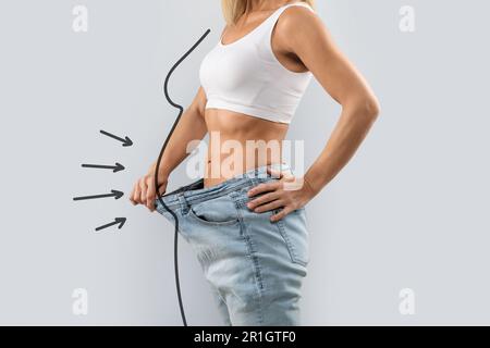 Corto di donna snella che indossa jeans oversize, mostrando vita sottile Foto Stock