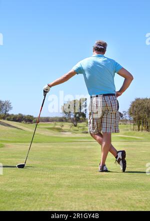 Golf, vista posteriore e vecchio con conducente all'aperto per allenamenti, hobby e sport su sfondo cielo blu. Club, dietro e attivo senior golfer maschio Foto Stock