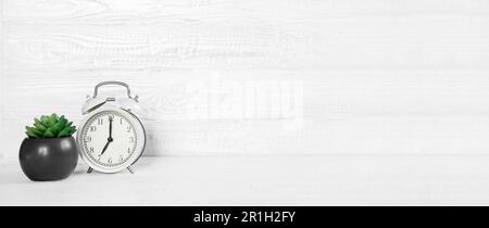 Scrivania bianca con vista frontale, sveglia, impianto di casa e area fotocopie. Banner di sfondo mattutino con spazio libero per il testo. Concetto minimalista, spazio di lavoro Foto Stock