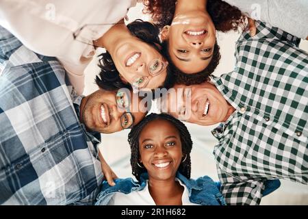 Bastone insieme, successo insieme. Ritratto ad angolo basso di un team di creativi accoccolati insieme in unità. Foto Stock