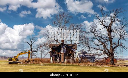 Paesaggio con una vecchia casa che viene demolita con un retroescavatore Foto Stock