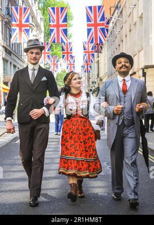 Londra, Regno Unito. 14th maggio, 2023. Due chiacchiera gentlemanly passeggiata con una giovane donna in abito popolare polacco lungo Jermyn Street. L'annuale Grand Flaneur Walk vede chaps e cappette, dandie e quaintrelle in impeccabile sartoria e stile che si sussurrano e si sfondano senza scopo intorno a St James' e le aree circostanti di Londra. La passeggiata inizia sempre presso la statua del dandy socialita Beau Brummell e lentamente si fa strada intorno alla zona. Credit: Imageplotter/Alamy Live News Foto Stock