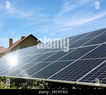 Pannelli solari vicino alle case sotto il cielo blu nelle giornate di sole. Fonte di energia alternativa Foto Stock