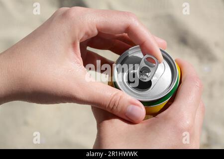 Donna apertura lattina con bevande frizzanti in spiaggia, primo piano Foto Stock