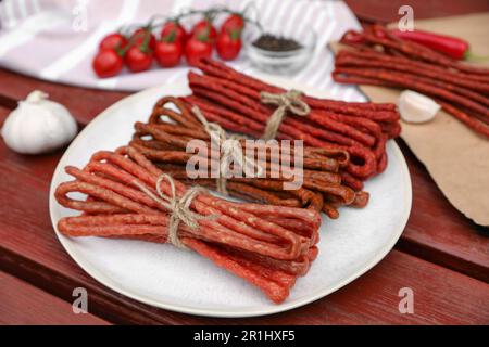 Pacchetti di kabanosy delizioso con aglio e pomodori su tavola di legno Foto Stock