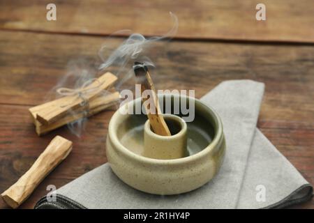 Bastone di palo Santo che frolla in supporto su tavolo di legno Foto Stock