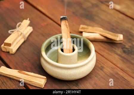 Bastone di palo Santo che frolla in supporto su tavolo di legno Foto Stock