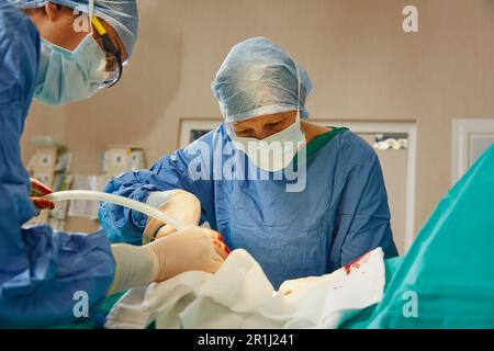 Rimanere concentrati sotto pressione. un team di chirurghi che eseguono un intervento chirurgico in una sala operatoria. Foto Stock