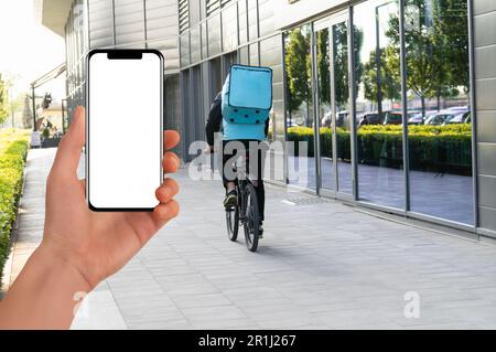 Mano con telefono su un corriere di consegna di fondo su una bici. Applicazione mobile per la consegna di alimenti. Foto di alta qualità Foto Stock