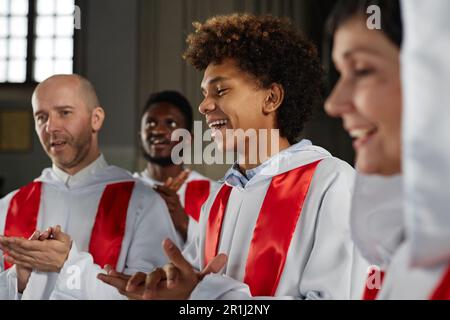Gruppo di persone felici dal coro della chiesa che cantano e battendo le mani durante lo spettacolo Foto Stock