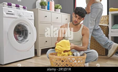 Due uomini si accoppiano a lavare i vestiti nella lavanderia Foto Stock