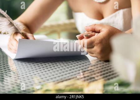 La sposa e lo sposo firmano un contratto di matrimonio. L'uomo tiene la mano della donna. Immagine a colori. Foto Stock