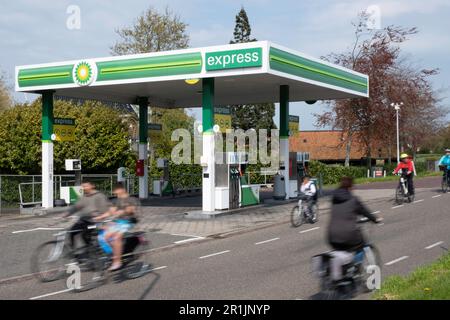 Stazione di servizio BP vuota lungo una strada con ciclista offuscata nel villaggio olandese di Lemmer nei Paesi Bassi. Transizione nella mobilità Foto Stock