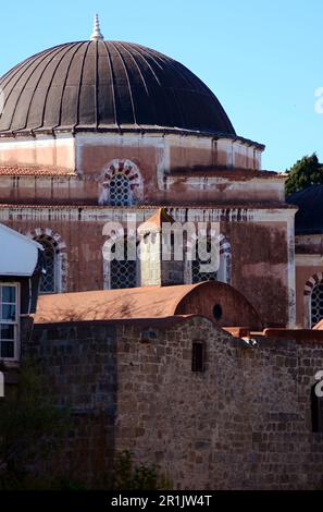 La cupola della moschea rosa di Suleiman il magnifico sull'isola di Rodi. Finestre barrate, pareti rosa, tetti adiacenti di una cappella cristiana Foto Stock