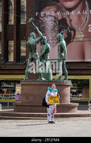 Studente di ingegneria che vende Äpy, la rivista biennale dell'umorismo, alla statua di Three Smiths a Helsinki, Finlandia Foto Stock