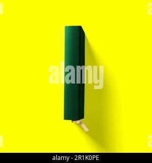 Concetto di ritorno a scuola , copertina rigida libro verde scuro gira vicino isolato su giallo. Foto Stock