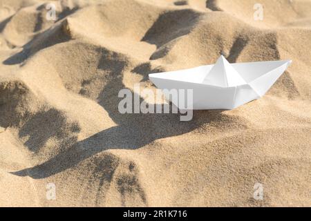 Una barca di carta bianca sulla spiaggia sabbiosa, spazio per il testo Foto Stock