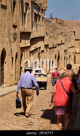 Via dei Cavalieri nella città medievale di Rodi. I turisti camminano lungo la strada, oltrepassando le residenze, la casa dei cavalieri. Foto Stock