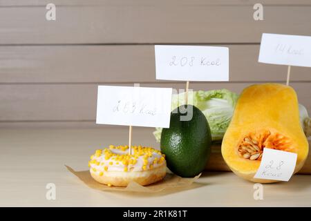 Prodotti alimentari con etichette di potere calorifico su tavola di legno, spazio per testo. Concetto di perdita del peso Foto Stock