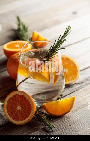 Gin tonic con ghiaccio, rosmarino e fette di arancia in vetro smerigliato.  Cocktail con ingredienti su un vecchio tavolo di legno. Spazio di copia  Foto stock - Alamy
