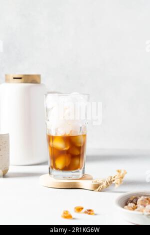 Caffè nero con ghiaccio e panna in un bicchiere alto. Chicchi di caffè. Foto Stock