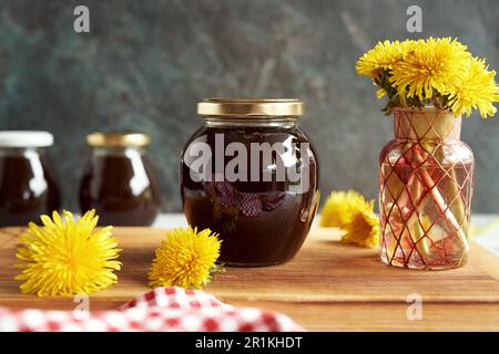 Un vasetto di vetro del cosiddetto miele di dente di leone - sciroppo fatto in casa da fiori freschi di Taraxacum in primavera Foto Stock