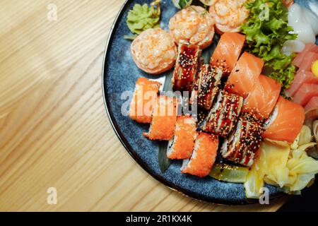Sushi misto con nigiri, panini e sashimi serviti in tradizionale piatto rotondo giapponese nero Sushioke. Foto Stock