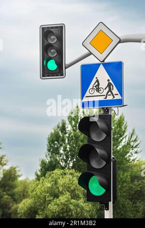 Posta con le indicazioni stradali Priority Road e Pedestrian, vicino al semaforo all'aperto Foto Stock