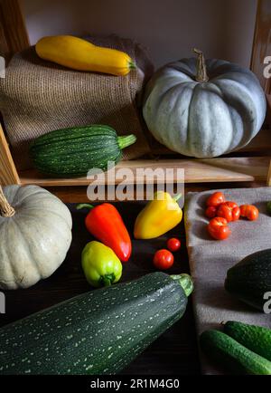 Midollo vegetale e zucche su scaffali di legno a casa, la vita ferma di cibo biologico. Zucchine, peperoni dolci e pomodori in un ambiente rustico. Raccolto, Foto Stock