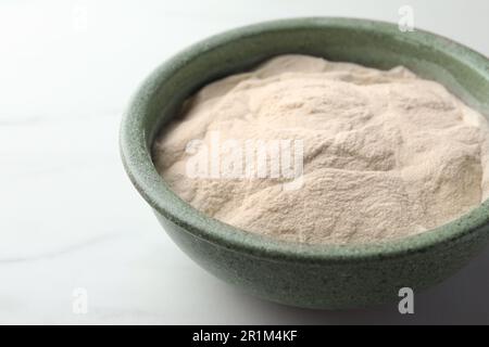 Ciotola di agar-agar polvere su tavolo bianco, primo piano Foto Stock