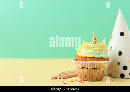 Cute dolce unicorno cupcake e gli elementi di festa sul tavolo giallo, spazio per il testo Foto Stock