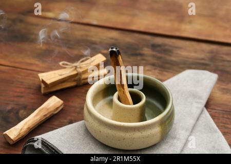 Bastone di palo Santo che frolla in supporto su tavolo di legno Foto Stock