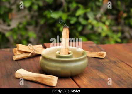 Bastone di palo Santo che frolla in supporto su tavolo di legno all'aperto Foto Stock