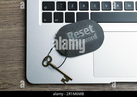 Chiave con password DI REIMPOSTAZIONE tag e computer portatile su tavolo in legno, vista dall'alto Foto Stock