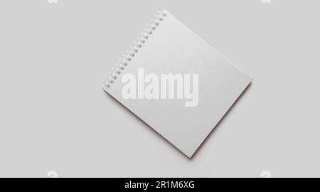 Taccuino bianco vuoto con ombre morbide su fondo in cemento grigio neutro. Foto Stock