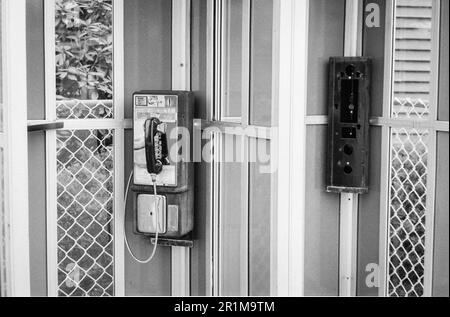 Un telefono cellulare vintage che lavora è appeso in una cabina telefonica in una fermata di riposo pubblica autostrada nel New Hampshire. Questa immagine è stata ripresa su pellicola analogica in bianco e nero. Foto Stock